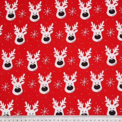 Smiling reindeer faces printed on a red polycotton fabric with a cm ruler