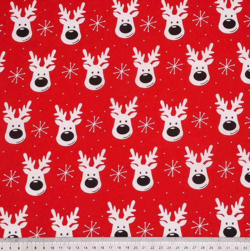 Smiling reindeer faces printed on a red polycotton fabric with a cm ruler