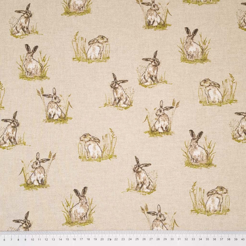 Hares in grassy patches printed on a panama linen look fabric with a cm ruler
