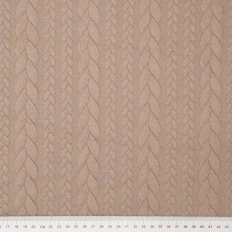 A plain sand coloured cable knit fabric with a cm ruler