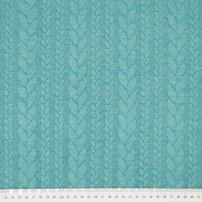 A plain petrol coloured cable knit dressmaking fabric with a cm ruler
