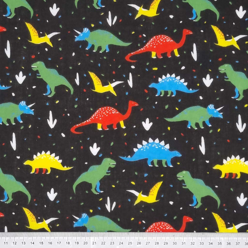 Colourful dinosaurs are printed on a black polycotton fabric with a cm ruler
