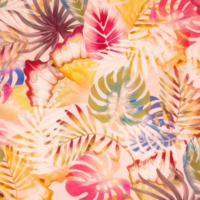 Tropical leaves printed on a coral coloured viscose dressmaking fabric