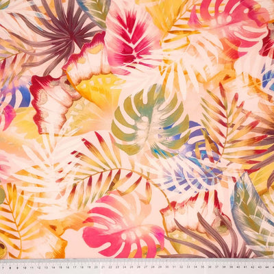Tropical leaves printed on a coral coloured viscose dressmaking fabric with a cm ruler