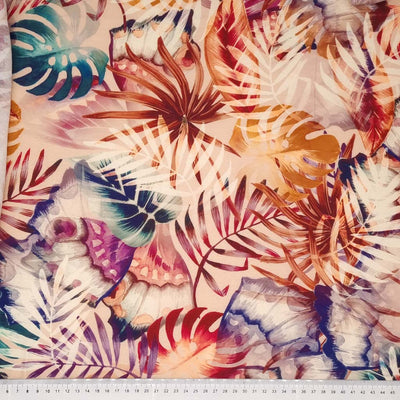 Multicoloured leaves are printed on a viscose dressmaking fabric with a cm ruler