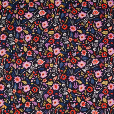 Pink flowers and happy, dancing skeletons are printed on an indigo 100% cotton, halloween fabric