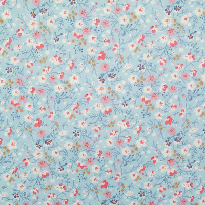 White, pink and blue ditsy flowers are printed on a sky blue polycotton fabric