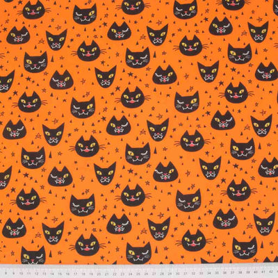 Black winking cats printed on an orange halloween polycotton fabric