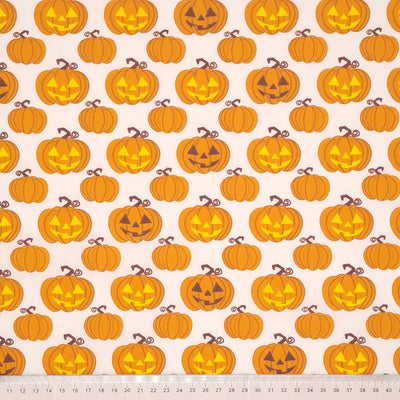 Glowing pumpkins are printed on a white polycotton fabric with a cm ruler at the bottom