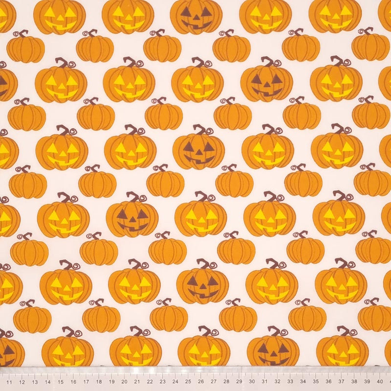 Glowing pumpkins are printed on a white polycotton fabric with a cm ruler at the bottom