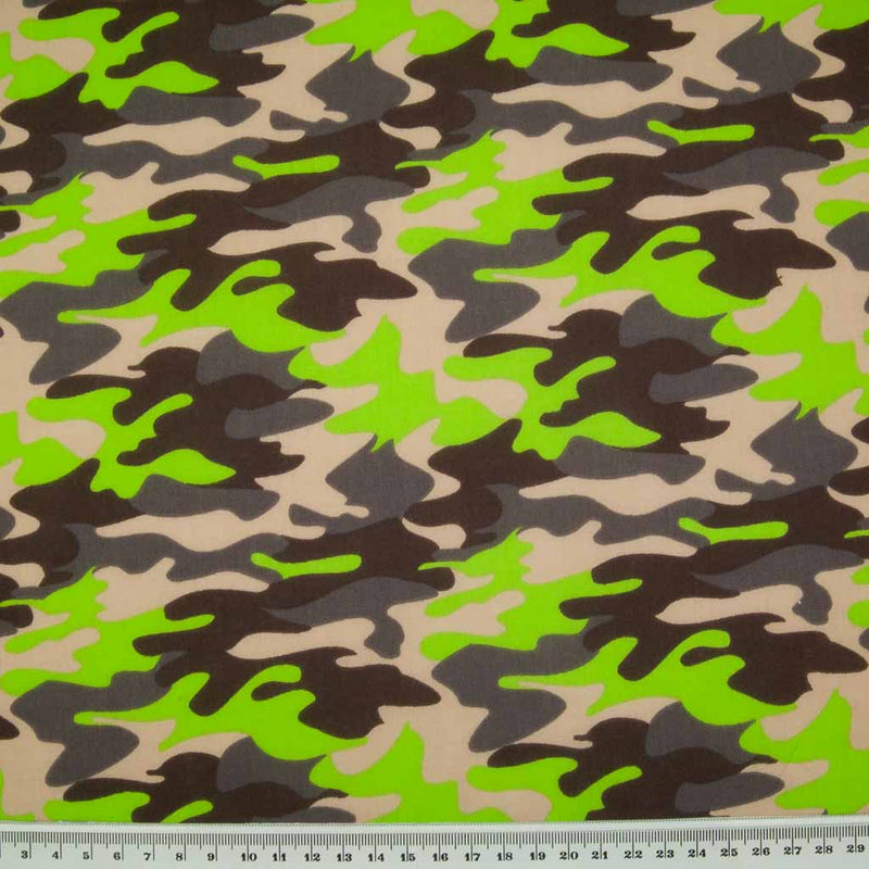 A camouflage design in beige, brown and green on a polycotton fabric with a ruler for size perspective