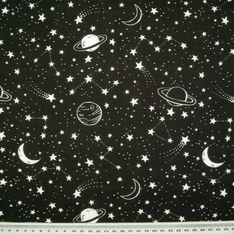 White stars, planets and moons are printed on a black polycotton fabric with a ruler at the bottom for size perspective