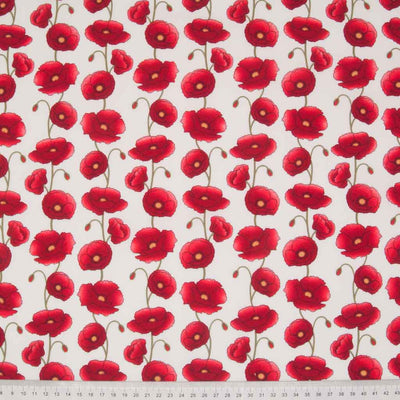Columns of pretty red poppies are printed on an ivory cotton poplin fabric with a cm ruler at the bottom