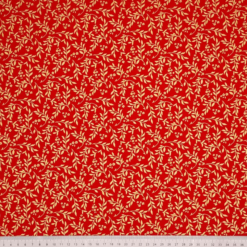 Printed gold metallic wreath leaves and flowers are printed on this red 100% cotton fabric with a cm ruler at the bottom