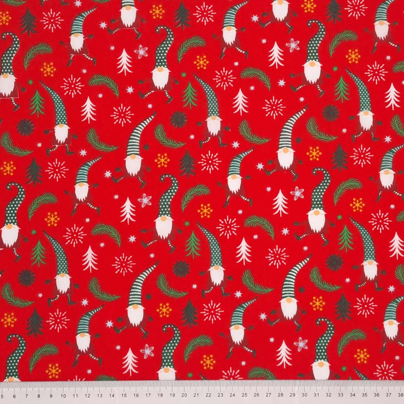 ancing and prancing Christmas gonks surrounded by scattered stars, snowflakes and leaves are printed on a red polycotton fabric with a cm ruler at the bottom