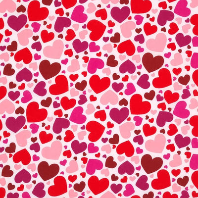 Brightly coloured falling hearts printed on a white polycotton fabric. 