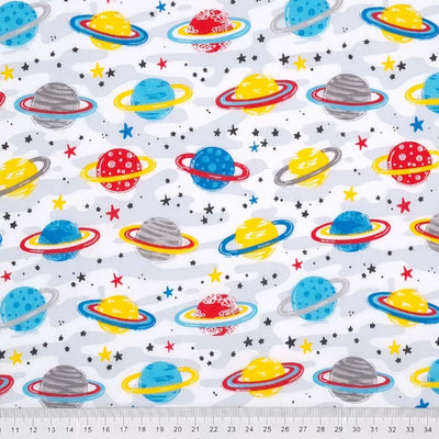 Brightly coloured planets with milky way stars printed on a white polycotton fabric with a cm ruler at the bottom