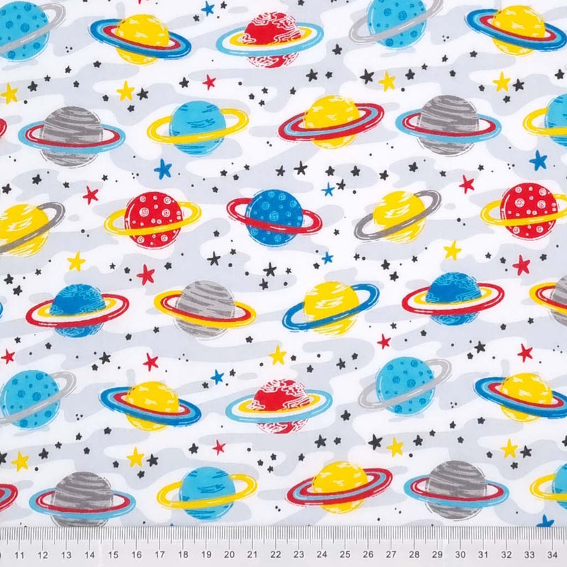 Brightly coloured planets with milky way stars printed on a white polycotton fabric with a cm ruler at the bottom