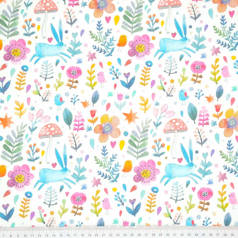 A blue rabbit, red toadstool, orange flowers and pink birds printed on a fat quarter of cotton fabric with a cm ruler at the bottom