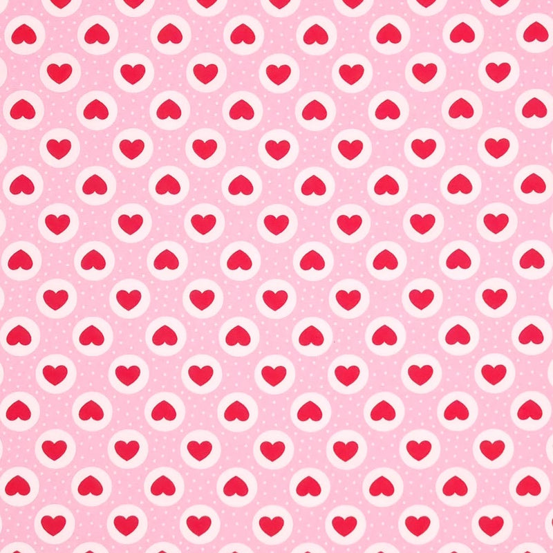Red hearts and small white spots are printed on a pink cotton poplin fabric by Rose & Hubble