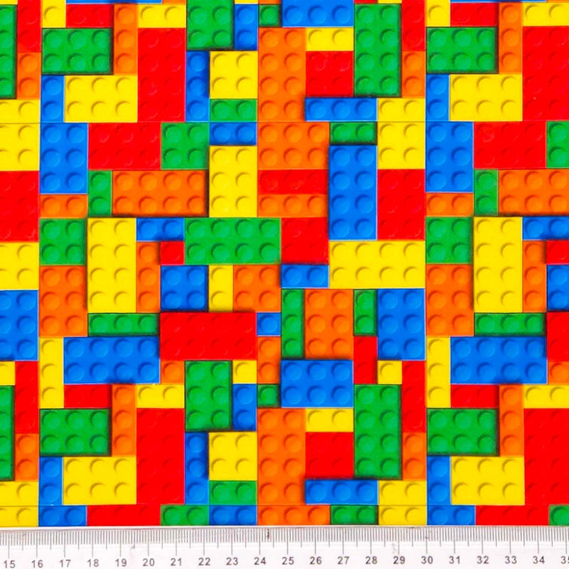 Colourful pattern of interlocking bricks printed on a cotton fabric with a ruler at the bottom for scale