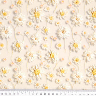 Pattern of white flowers with yellow centers on a light beige background printed on a cotton fabric
