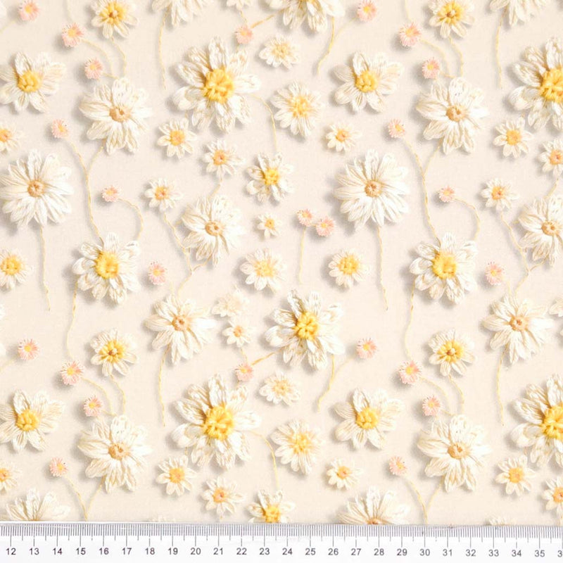 Pattern of white flowers with yellow centers on a light beige background printed on a cotton fabric