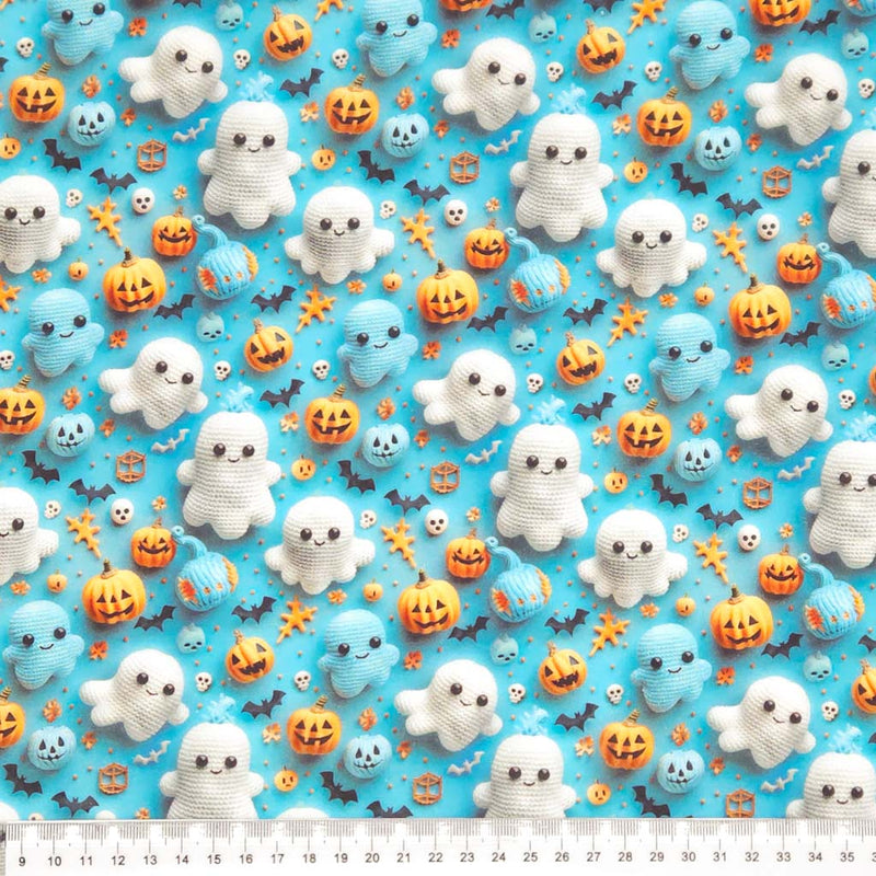 Halloween-themed fabric with crochet ghosts, pumpkins, and bats on a blue cotton fabric