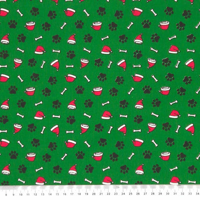 Doggy paws and santa hats printed on a green polycotton fabric with a cm ruler