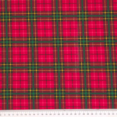 A red tartan design printed on a polycotton fabric with a cm ruler