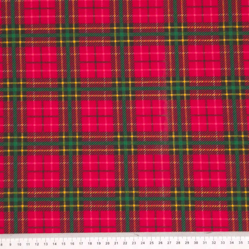 A red tartan design printed on a polycotton fabric with a cm ruler