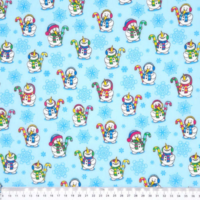 Festive snowmen printed on  blue polycotton fabric with a cm ruler