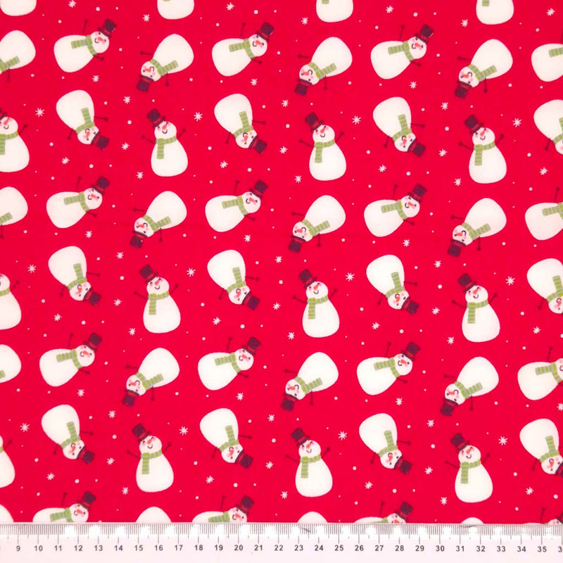 Festive snowmen printed on a red polycotton fabric with a cm ruler