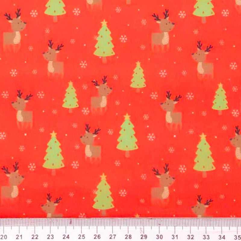 Christmas-themed fabric pattern with reindeer, trees, and snowflakes on a red background, measured against a ruler.