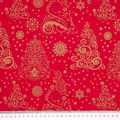 Large gold christmas trees printed on a red cotton fabric with a cm ruler