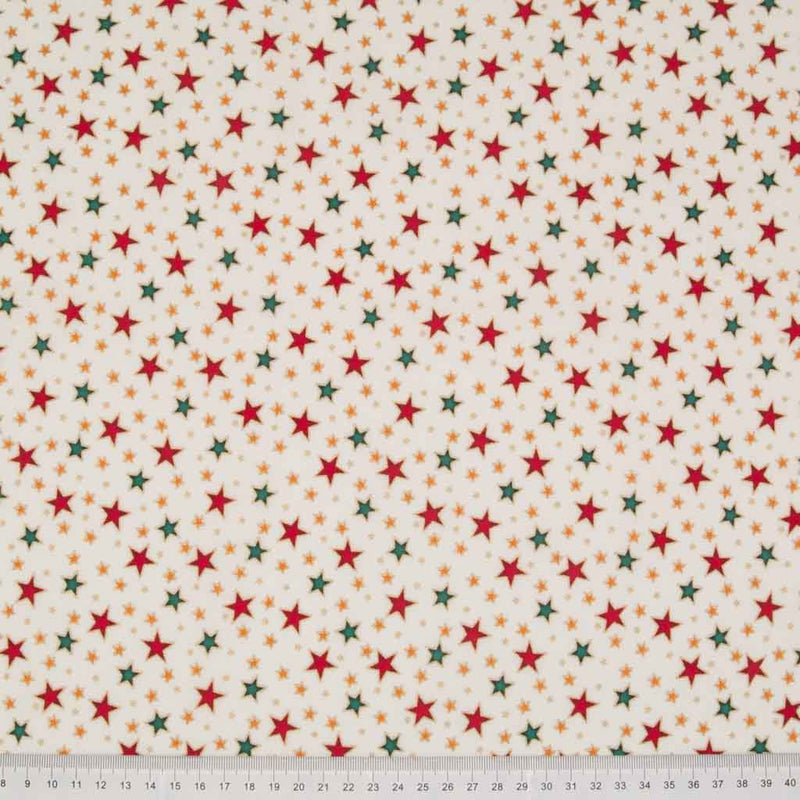 Red and green stars printed on an ivory cotton christmas fabric with a ruler