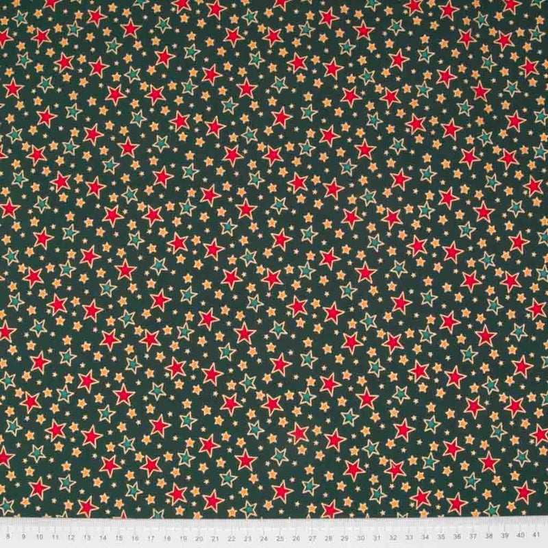 Red and green stars printed on a green cotton christmas fabric with a ruler