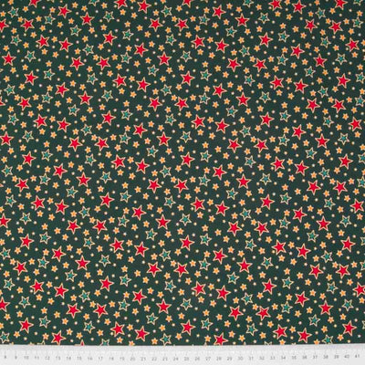 Red and green stars printed on a green cotton christmas fabric with a ruler