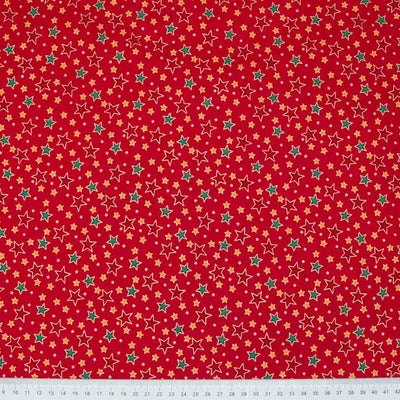 Red and green stars printed on a red cotton christmas fabric with a ruler