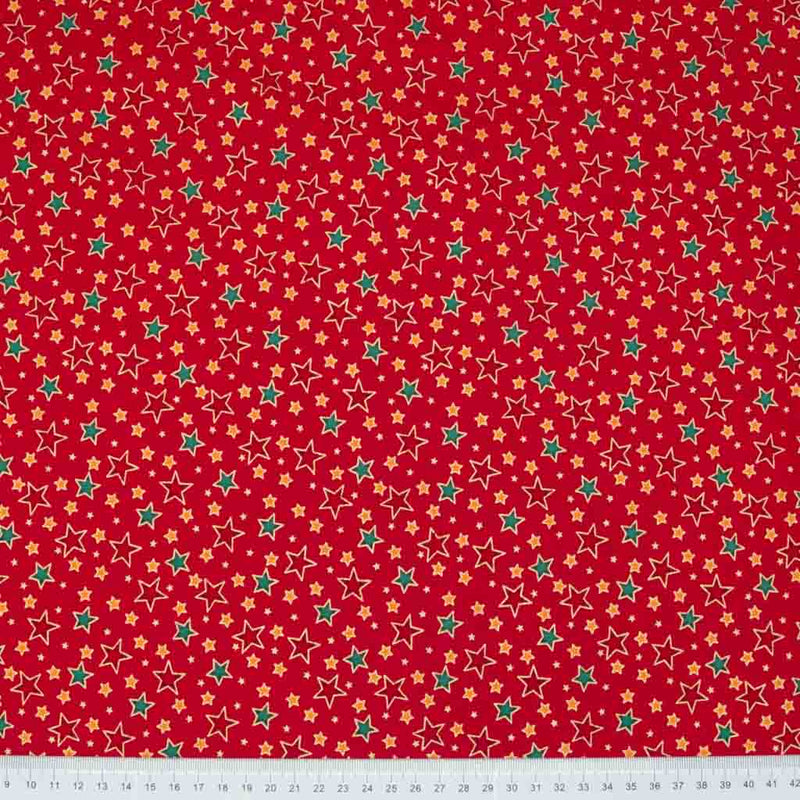 Red and green stars printed on a red cotton christmas fabric with a ruler