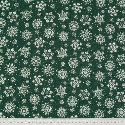 White snowflakes printed on green polycotton fabric