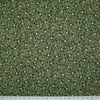 Mini holly leaves in gold and green are printed on a christmas cotton fabric