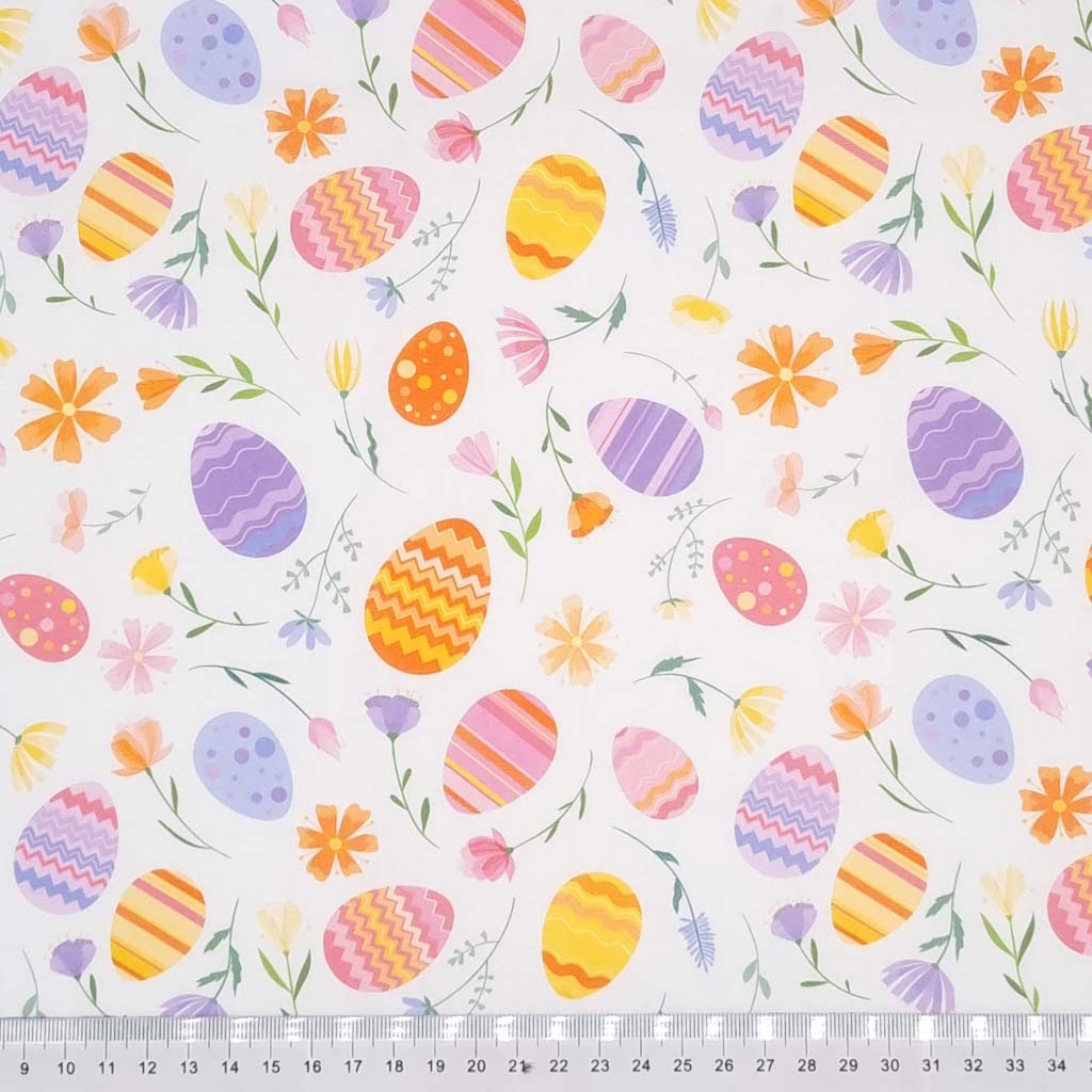 Easter eggs and flowers are printed on a white cotton fabric with a cm ruler