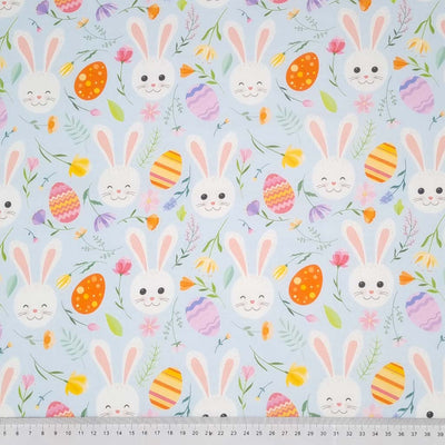 Easter fabric with bunny faces and easter eggs on a pastel blue cotton fabric with a cm ruler