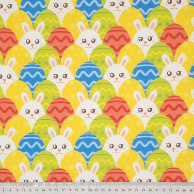 Bunnies hiding amongst easter eggs is printed on a cotton fabric by Rose & Hubble with a cm ruler