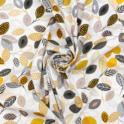 Detailed floral print of leaves in neutral shades of grey, black and yellow; printed on a white 100% cotton fabric
