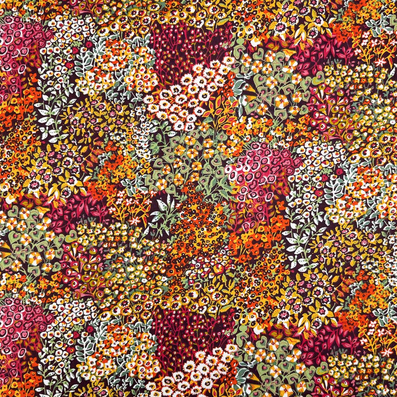 Intricate wildflowers and vines, in summer shades of orange, pink and yellow, printed on a deep black 100% cotton fabric
