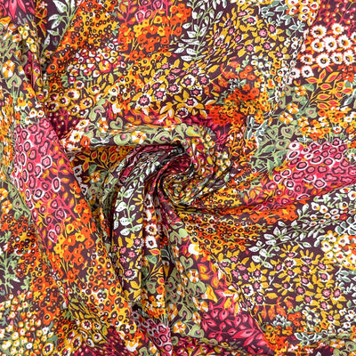 Intricate wildflowers and vines, in summer shades of orange, pink and yellow, printed on a deep black 100% cotton fabric