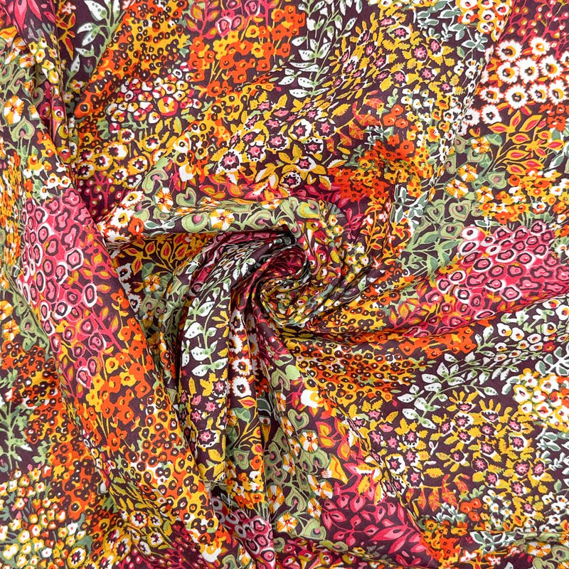Intricate wildflowers and vines, in summer shades of orange, pink and yellow, printed on a deep black 100% cotton fabric
