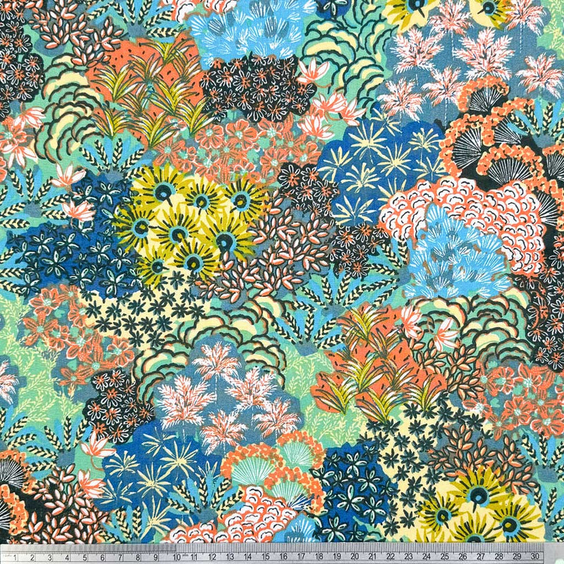 A bright fabric with multicoloured flower displays printed on a dark dressmaking cotton fabric with a cm ruler